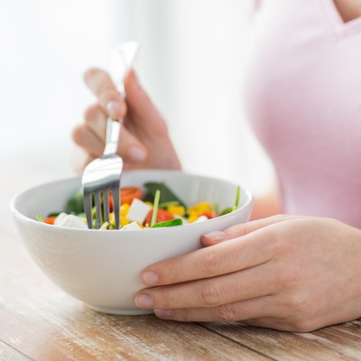 close up of young woman eating salad at home