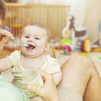 father feeding his cheerful baby