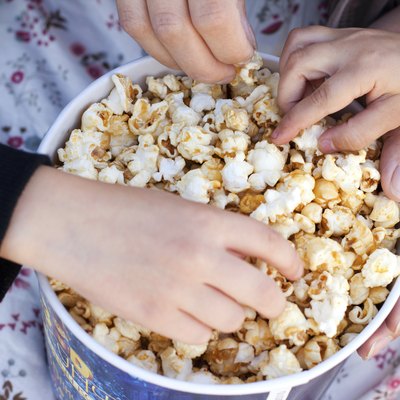 Children eat popcorn out of a paper bucket, close-up