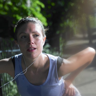 Young woman stretching by fence on street