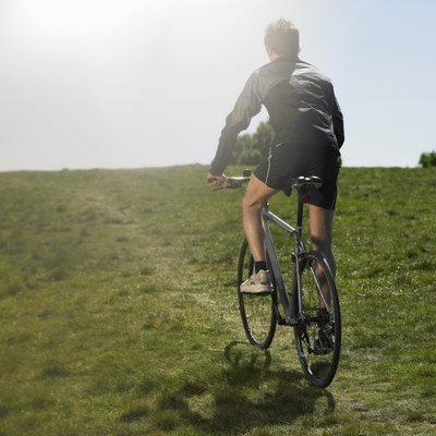 Mid adult man riding bicycle uphill, rear view