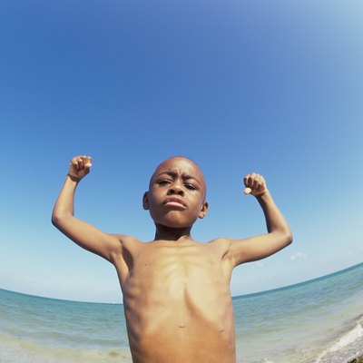 Low angle view of a boy flexing his muscles on the beach