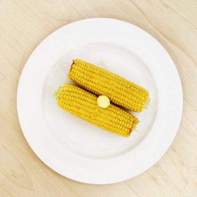 Elevated view of two corncobs topped with butter
