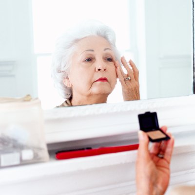 portrait of an elderly woman applying makeup