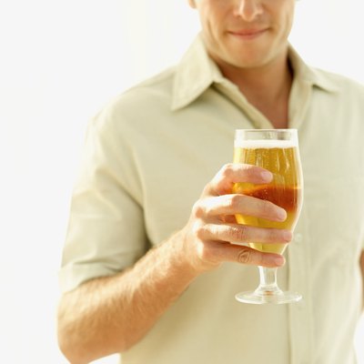 mid section view of a mid adult man holding a glass of beer