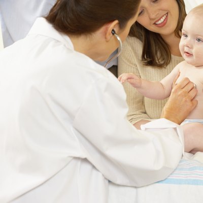Side profile of a female doctor examining a baby boy with a stethoscope