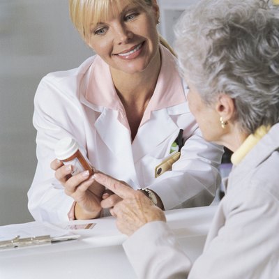 Woman and pharmacist looking at bottle of prescription medicine