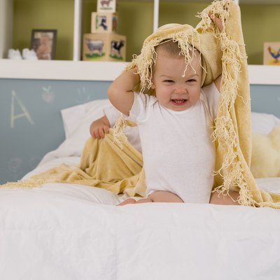 Child playing with blanket on bed