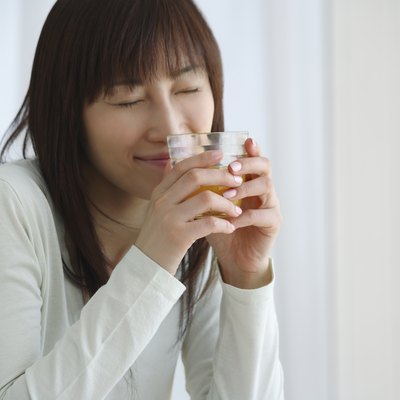 Young Woman Holding a Glass of Orange Juice, Side View