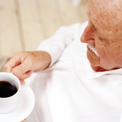 high angle view of an elderly man holding a cup of black coffee