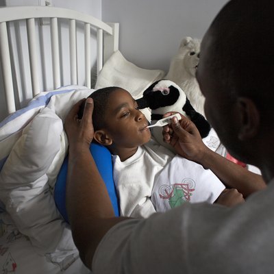 Father checking son's temperature with thermometer, elevated view