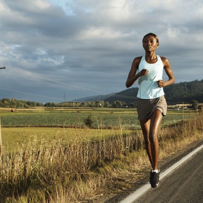 Young woman jogging by road in rural landscape