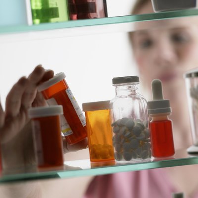 Woman taking pills from medicine cabinet