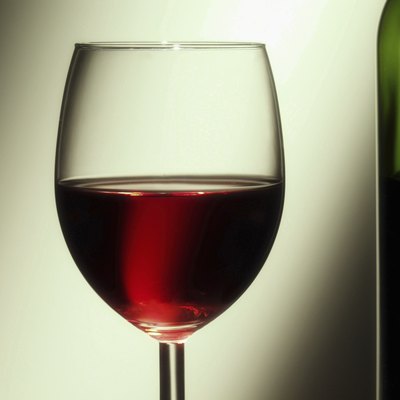 Glass of red wine besides wine bottle