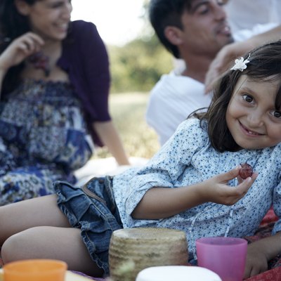 girl eating grape, family behind