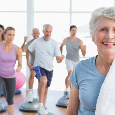 Senior woman with people exercising in fitness studio