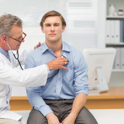 Mature doctor listening to his patients chest with stethoscope