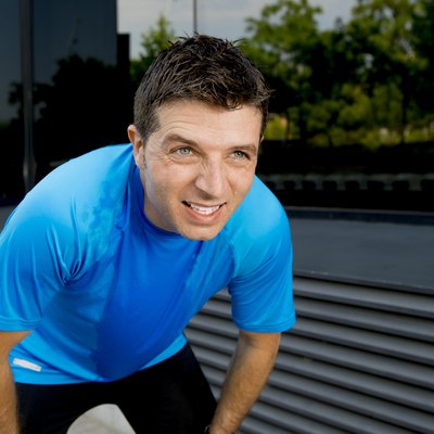 young attractive man leaning exhausted after running session sweating