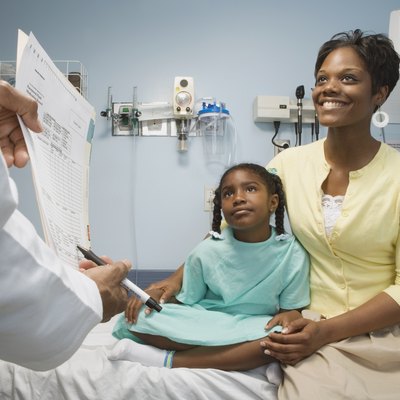 African girl in hospital bed with mother talking to doctor