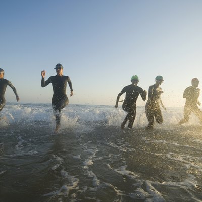 Multi-ethnic swimmers running in surf