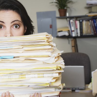 Surprised woman behind stack of files