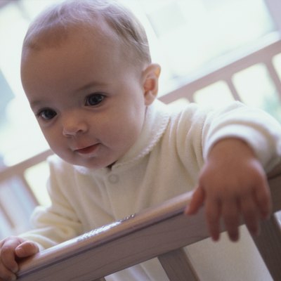 Close-up of a baby boy holding the railing of a crib