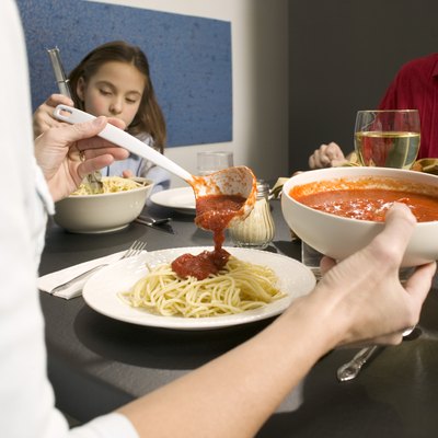 Woman pouring tomato sauce on pasta