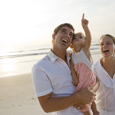 Cheerful young couple with daughter on the beach