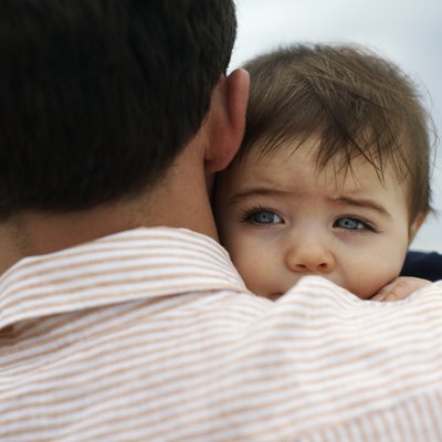 Father carrying baby daughter (15-18 months) outdoors, close-up