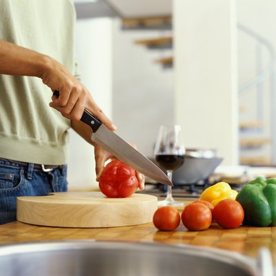 mid section view of a man cutting red bell pepper in the kitchen