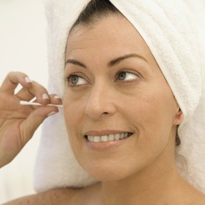 Mid adult woman cleaning her ear with a cotton swab