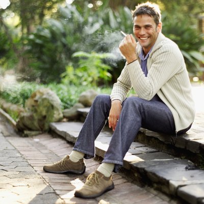 Portrait of a man sitting on steps holding a cigarette