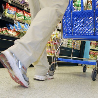 Low section view of a person walking with a shopping cart in a supermarket