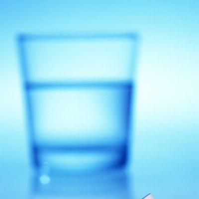 close-up of tablets lying beside a glass of water