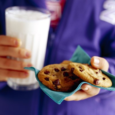Child's hands holding cookies and milk
