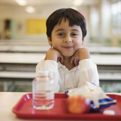 Boy with lunch sitting in school cafeteria