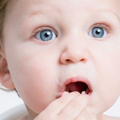Head shot of toddler eating with surprised expression