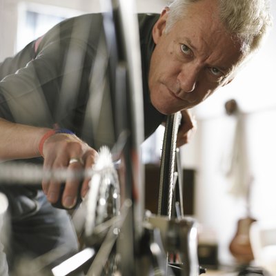 Mature man holding bicycle pedal, looking at wheel