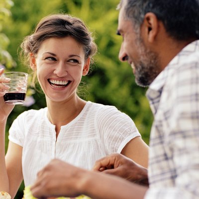 Couple dining outdoors, woman looking at man, laughing
