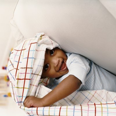 Young Boy Sitting on a Chair and Playing Under a Sheet