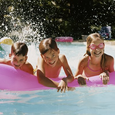 Three children in a Swimming Pool Playing With an Air Bed