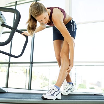 low angle view of a young woman on a treadmill holding her calf
