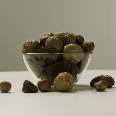 Assortment of nuts lying in glass bowl and around, studio shot, close-up