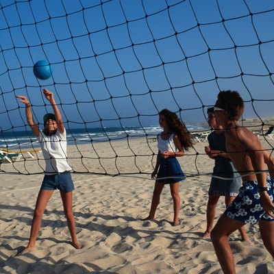 Teenage girls and boys (16-17) playing beach volley ball