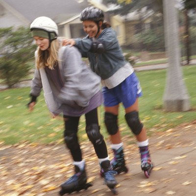 Two teenage girls (14-15) inline skating in park
