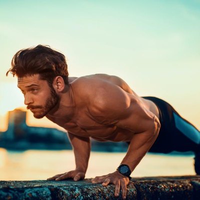 Picture of a young athletic man doing push ups outdoors.