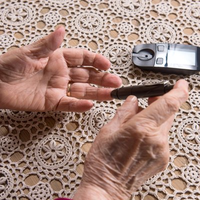 Old woman with glucometer checking blood sugar level