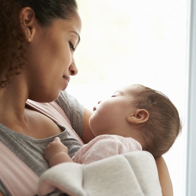 Close Up Of Mother Cuddling Baby Daughter At Home