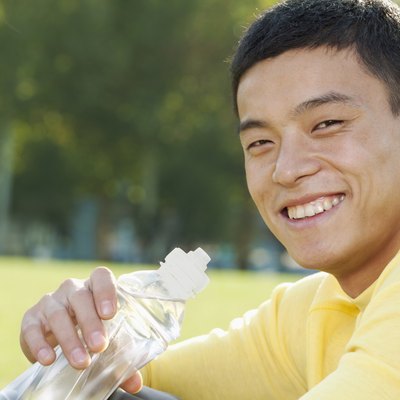 Young Athletic Man Sitting on the Grass in a Park, Close Up