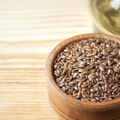 Flax seeds in wooden bowl , linseed oil on wooden background